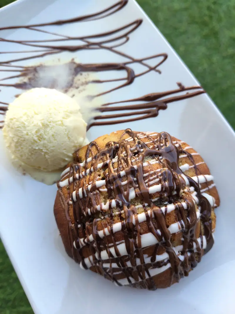 Cookie templada emplatada con helado y salsas de chocolate