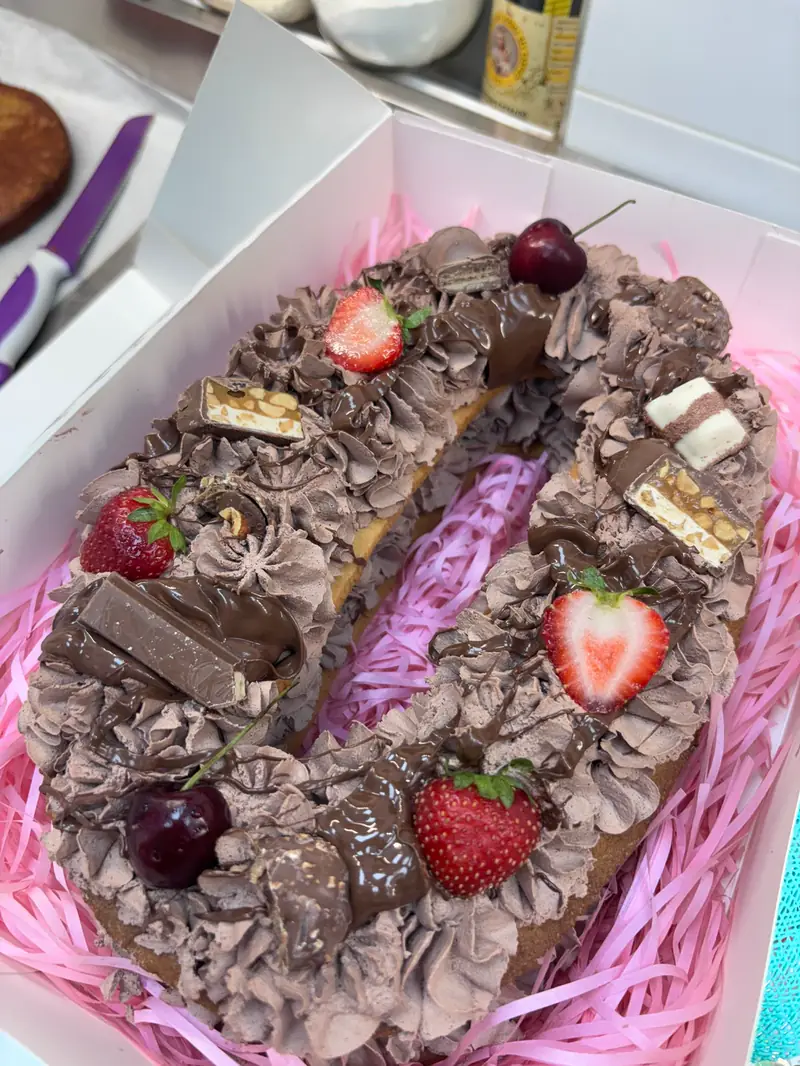 Tarta con forma de número ocho decorada con crema de chocolate, fresas y bombones